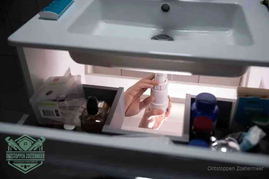 Een pompfles met zeep boven een wastafel, de heet water en afwasmiddel-methode om een vetprop in de afvoer los te maken in Zoetermeer