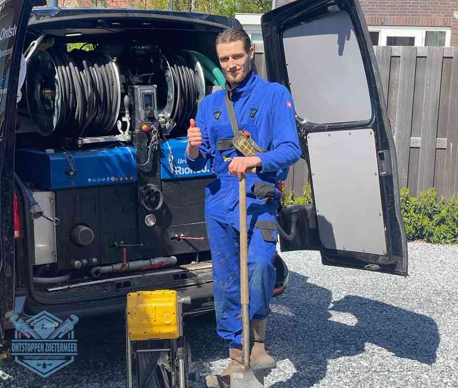 Een monteur bij de werkbus met grote hogedruk-slanghaspels, apparatuur voor hardnekkige afvoerverstoppingen in Zoetermeer