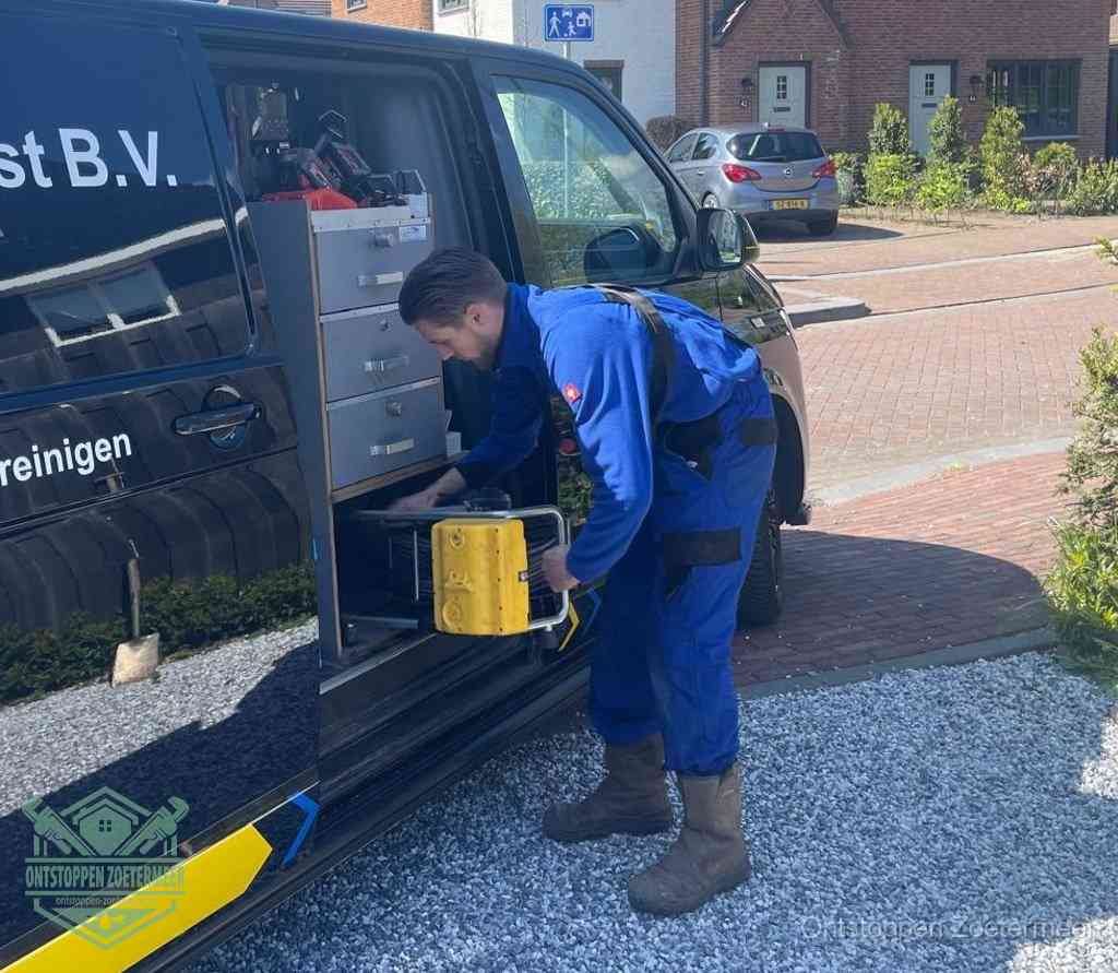 Een monteur pakt buiten op de oprit gereedschap uit de bedrijfsbus, het moment om een professional in te schakelen voor een verstopte afvoer in Zoetermeer