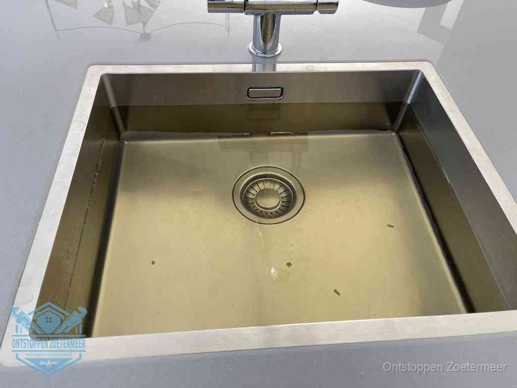 Stilstaand water in een rvs spoelbak dat niet wegloopt, een duidelijk signaal van een gootsteenverstopping in Zoetermeer
