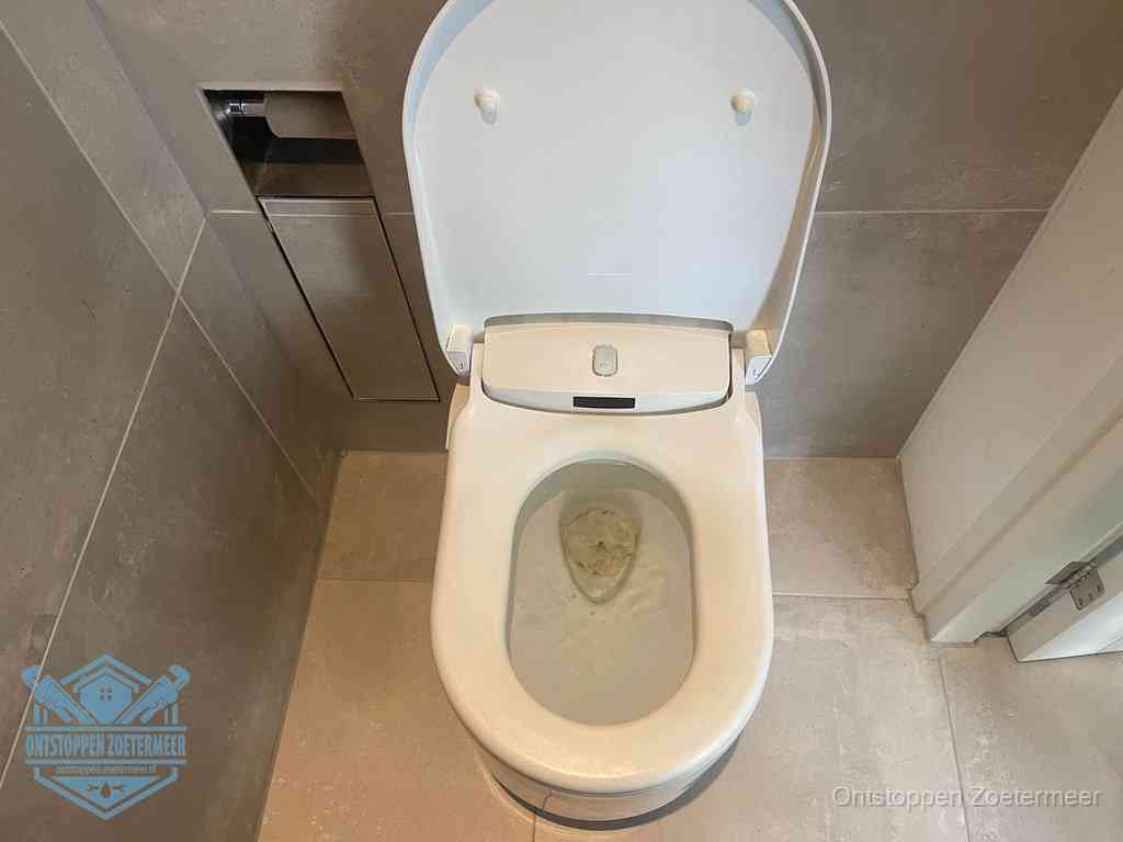 Een wit hangtoilet waarin een prop wc-papier op het water blijft drijven, een duidelijk signaal van een verstopte wc in Zoetermeer