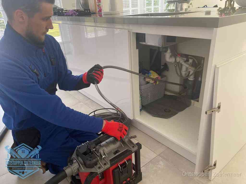 Een monteur reinigt de keukenafvoer grondig met een veermachine om terugkerende gootsteenverstoppingen te voorkomen in Zoetermeer