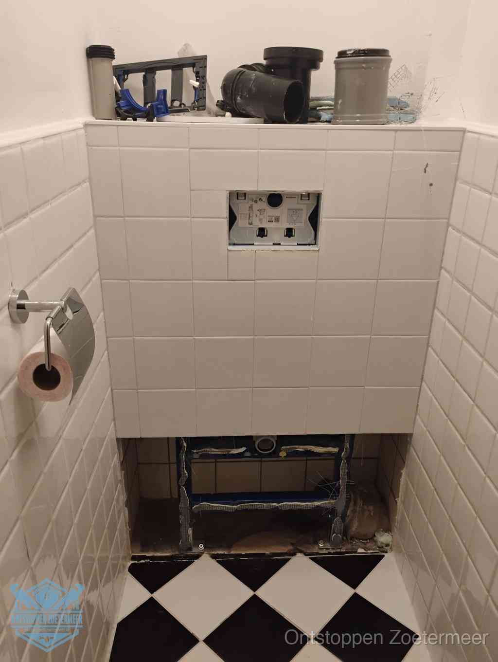 Een toiletruimte waar het hangtoilet en de inbouwreservoir-onderdelen zijn vrijgelegd voor onderhoud, periodiek nazicht voorkomt een wc-verstopping in Zoetermeer